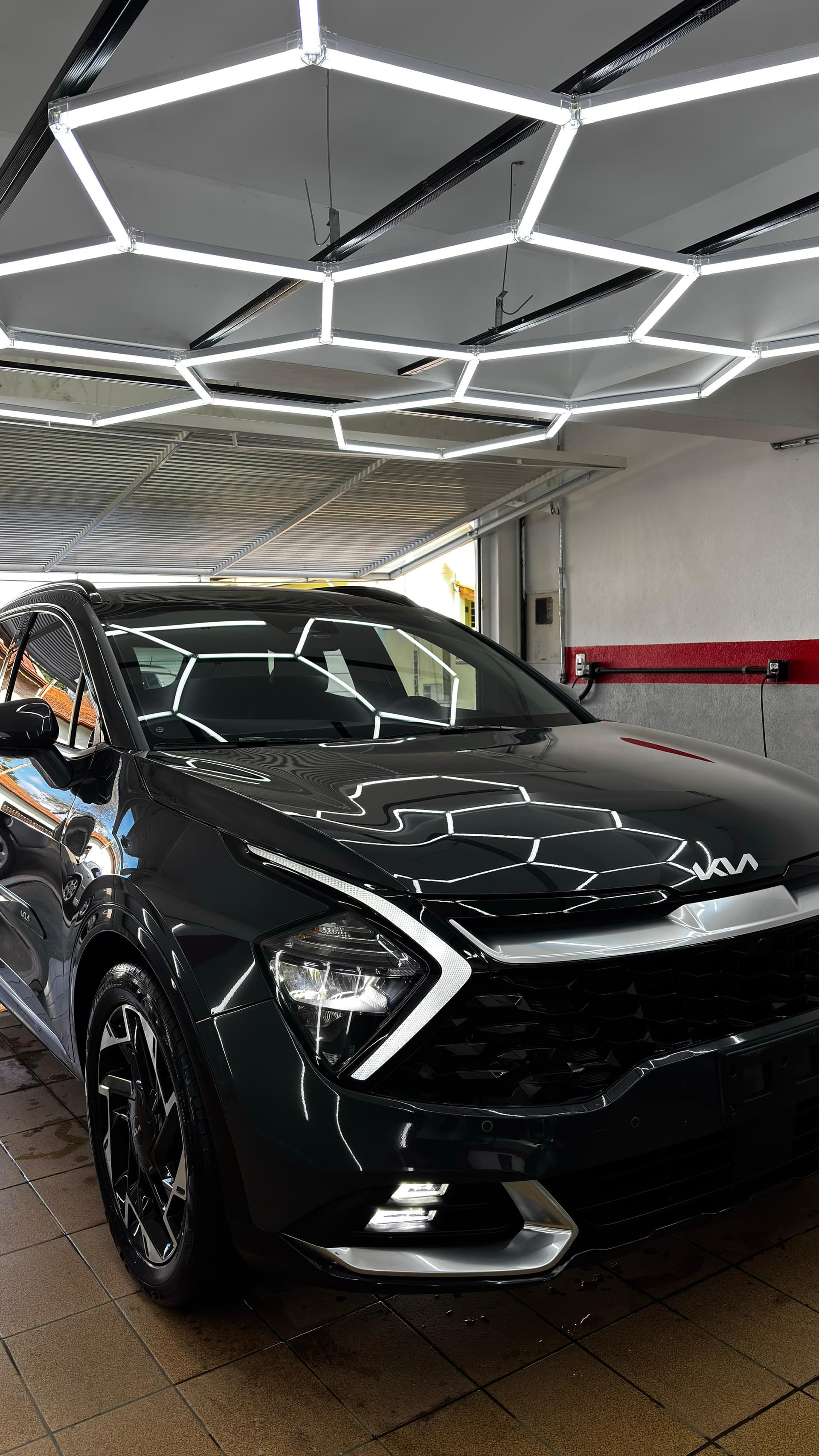 SUV Kia preto polido sob iluminação hexagonal na Garagem 65